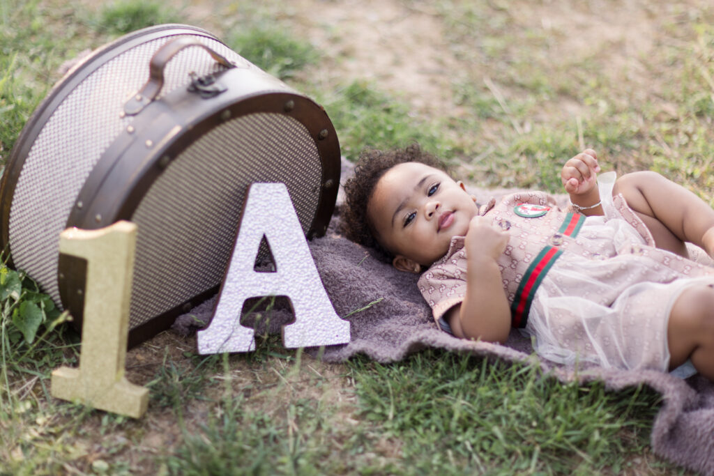 Baby girl wearing brown dress laying on the grass